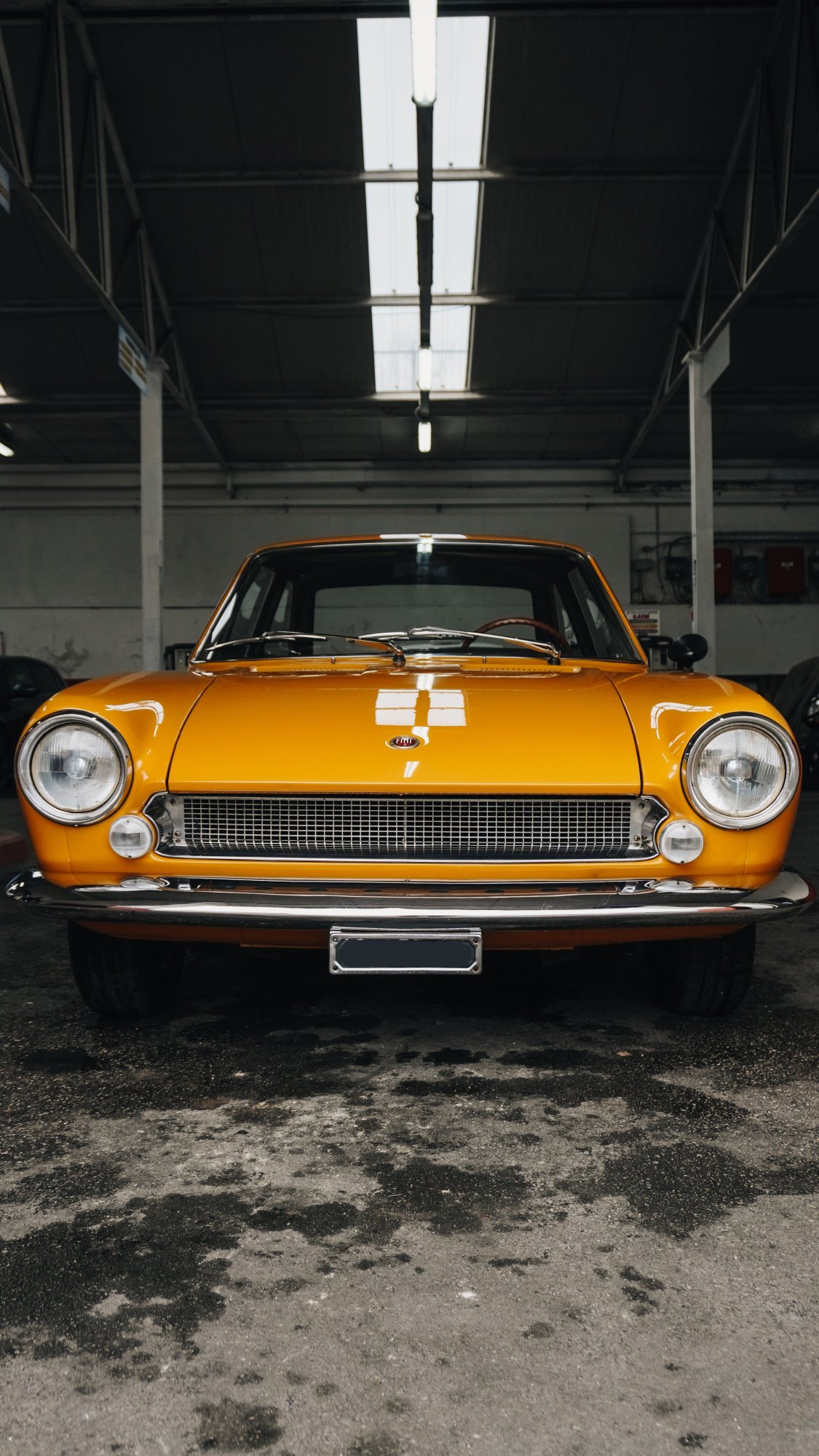 Front view of a restored orange classic coupe parked inside a workshop